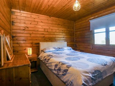 A bedroom with a bed and lamp at Lodge 2 - Bron Eifion
