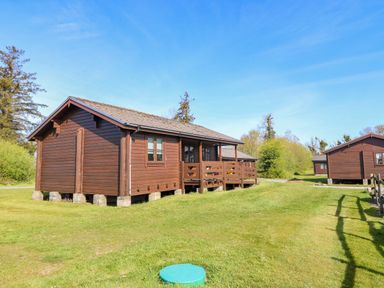A lodge with a deck and grass area at Lodge 2 - Bron Eifion