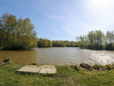 A view of a pond with trees and grass at Lodge 2 - Bron Eifion