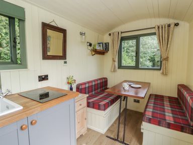 A dining area with a table and seating at The Three Spaniels Shepherds Hut in Cwrtnewydd near Llanybydder
