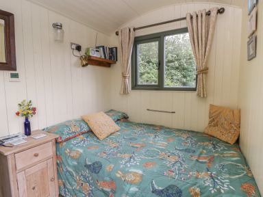 A bedroom with a bed and window at The Three Spaniels Shepherds Hut Cwrtnewydd near Llanybydder
