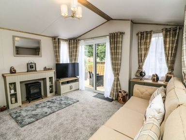 A living room with a television and a sofa at Hedgehog Lodge in Carnforth