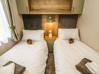 A bedroom with two beds and a bedside table at Hedgehog Lodge in Carnforth