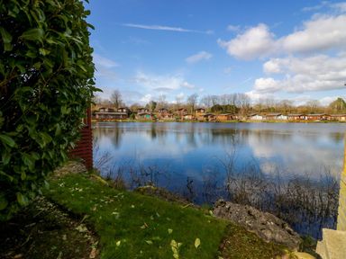 A view of a lake with houses beside it at Hedgehog Lodge in Carnforth