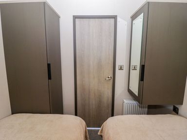 A bedroom with wardrobes and a door at Stone Crab Lodge in Haverfordwest