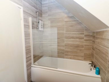 A bathroom with a bathtub and shower screen at 17 Fairfield Road