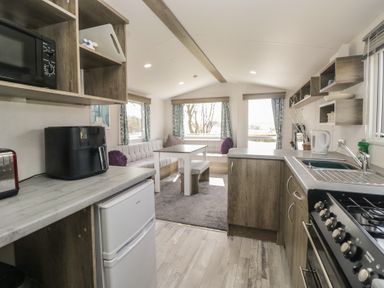 A kitchen with appliances and dining area at Standard Caravan at Three Lochs Holiday Park, Newton Stewart