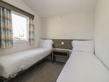 A bedroom with two beds and a window at Standard Caravan at Three Lochs Holiday Park in Newton Stewart
