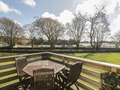 A deck with a table and chairs overlooking caravans at Standard Caravan at Three Lochs Holiday Park in Newton Stewart