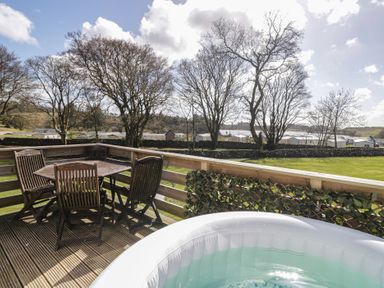 An outdoor area with a hot tub and a table with chairs at Standard Caravan at Three Lochs Holiday Park, Newton Stewart