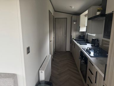 A kitchen with cabinets and appliances at Lochwood Platinum Superior at Three Lochs Holiday Park Newton Stewart