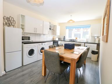 A kitchen with appliances and a dining table at The Mill House Gardens