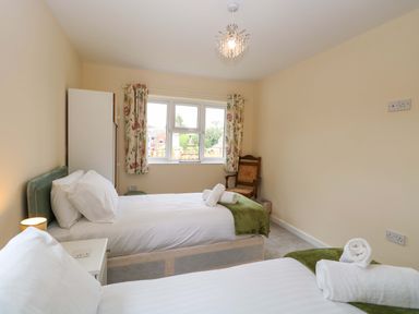 A bedroom with two beds and a wardrobe at The Mill House Gardens 