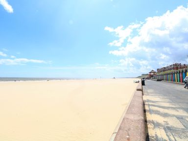 A beach scene with a boardwalk and colorful beach huts at The Mill House Gardens 