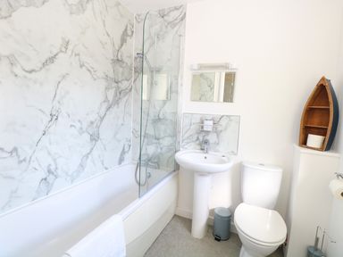 A bathroom with a bathtub and sink at The Mill House Gardens Oulton Broad