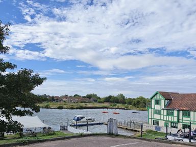 A view of a river with boats and a building at The Mill House Gardens Oulton Broad
