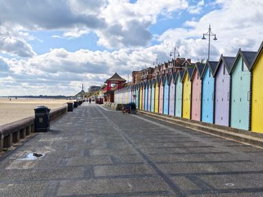 A pathway with beach huts along the side at The Mill House Gardens Oulton Broad