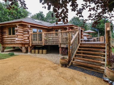 An outdoor area featuring a log cabin with a deck and steps at Copper Suite in Chulmleigh