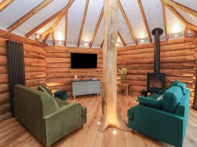 A living room with a log wall and sofas at Copper Suite in Chulmleigh