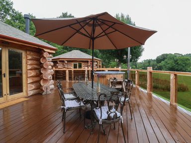 A deck with a table and chairs under an umbrella at Copper Suite in Chulmleigh