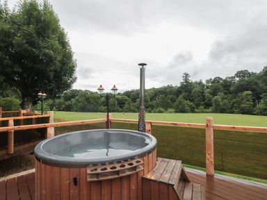 An outdoor area with a hot tub on a wooden deck at Copper Suite in Chulmleigh