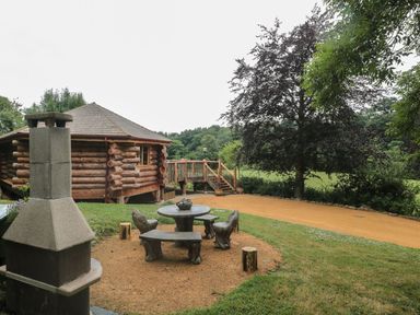 An outdoor area with a log cabin and wooden furniture at Copper Suite Chulmleigh