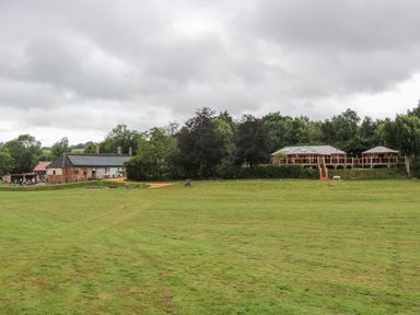 A grassy area with trees and buildings at Copper Suite Chulmleigh