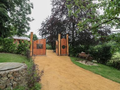 A garden entrance with wooden gates and a path at Copper Suite in Chulmleigh