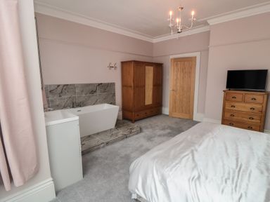 A bedroom with a bathtub and wardrobes at 5 Station Avenue