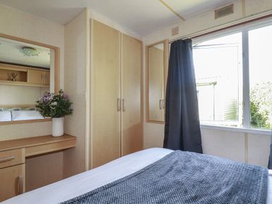 A bedroom with a bed, wardrobe, and flowers at Beech Lodge in Wadebridge