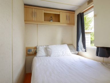 A bedroom with a bed and a window at Beech Lodge in Wadebridge