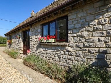 A stone cottage with flowers on the windowsill at Dunvant in Swanage
