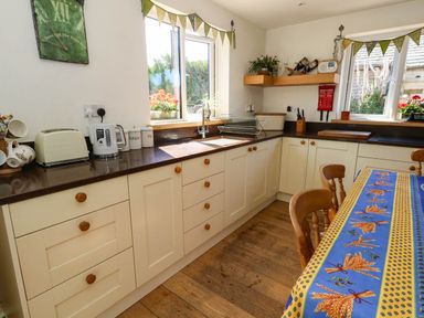 A kitchen with cabinets, sink, and a table at Dunvant in Swanage