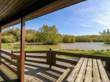 A deck with a view of a lake and trees at Lodge 6 - Sleep 4 - Twin and Double, Criccieth