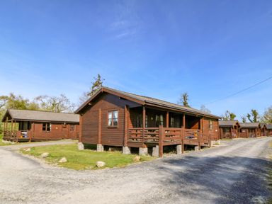 A row of wooden cabins along a gravel road at Lodge 6 - Sleep 4 - Twin and Double in Criccieth