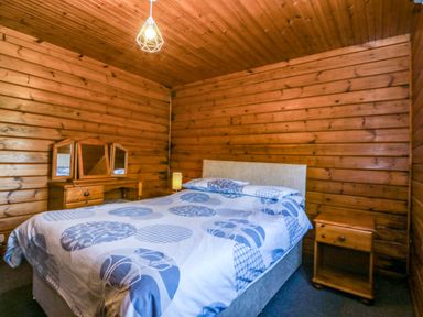A bedroom with a bed and bedside table at Lodge 6 - Sleep 4 - Twin and Double in Criccieth