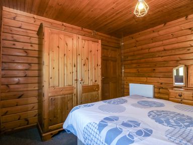 A bedroom with a bed and wardrobe at Lodge 6 - Sleep 4 - Twin and Double in Criccieth
