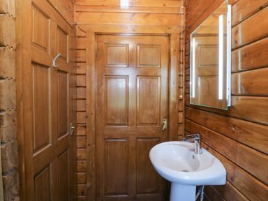 A bathroom with a sink and wood paneling at Lodge 6 - Sleep 4 - Twin and Double, Criccieth