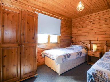 A bedroom with two beds and a wardrobe at Lodge 6 - Sleep 4 - Twin and Double in Criccieth