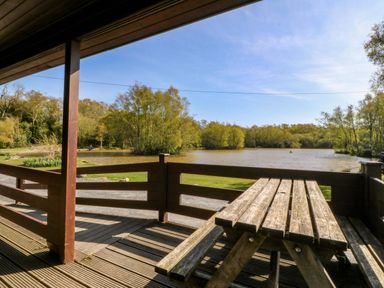An outdoor area with a table and bench overlooking a pond at Lodge 6 - Sleep 4 - Twin and Double in Criccieth