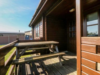 An outdoor patio area with a table and benches at Lodge 6 - Sleep 4 - Twin and Double in Criccieth