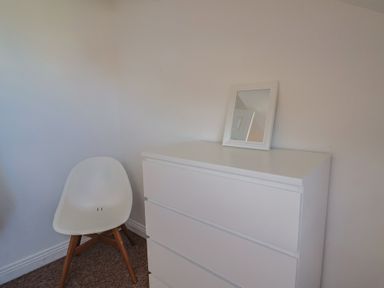 A bedroom with a dresser and a chair at 2 Lyme Mews in Seaton