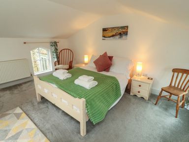 A bedroom with a bed, towels, lamp, chair at Juniper Hayloft in Ambleside