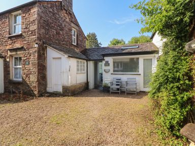 A house with chairs and gravel area at Juniper Hayloft in Ambleside