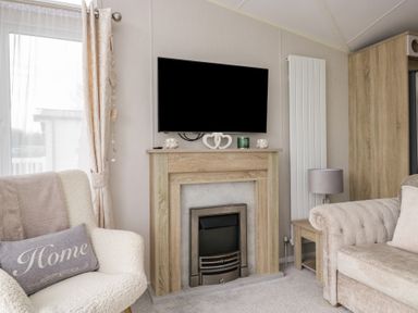 A living room with a television and a fireplace at Swan Haven in Grange-Over-Sands