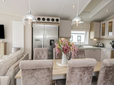 A kitchen with a dining area and a refrigerator at Swan Haven in Grange-Over-Sands