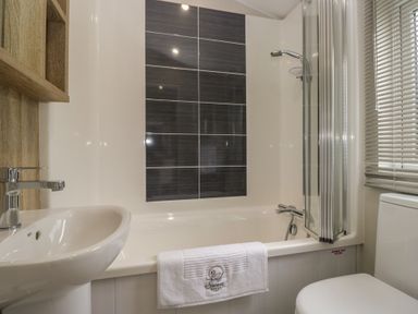 A bathroom with a bathtub, sink and shower at Swan Haven in Grange-Over-Sands