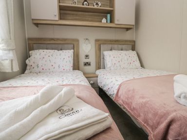 A bedroom with two single beds and towels at Swan Haven in Grange-Over-Sands