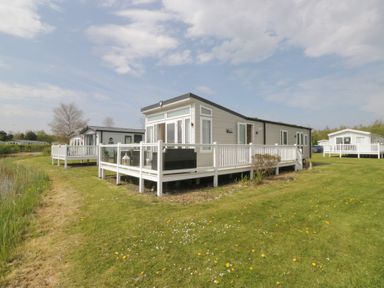 A mobile home with a deck situated near a lake at Swan Haven in Grange-Over-Sands