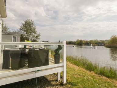 An outdoor patio with furniture overlooking a lake at Swan Haven in Grange-Over-Sands